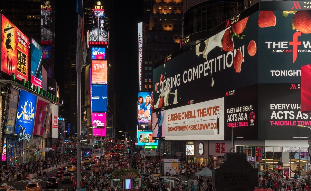 Menu Times Square buzzing with nightlife, neon signs, and crowds in New York City.